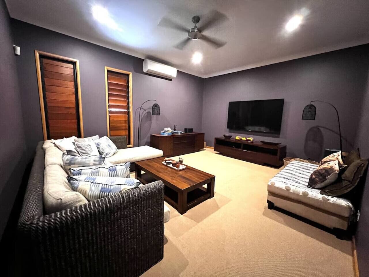 Un soggiorno con un divano, una piccola poltrona, un tavolino, una televisione e una ventola a soffitto.