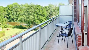 A balcony with a table and chairs, overlooking a pond and greenery. - Apartment, Dornumersiel (Dornum)