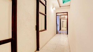 A corridor with doors, a tiled floor, and a ceiling light. - Hotel O Adarsh Nagar Metro Station (New Delhi)