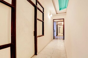A corridor with doors, a tiled floor, and a ceiling light. - Hotel O Adarsh Nagar Metro Station (New Delhi)