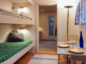 A compact room with a bunk bed, a dining table set for four, and a window with a view of the sky. - 3 Person Holiday Home in Hunnebostrand (Hunnebostrand)