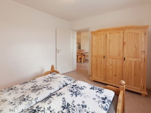 Une chambre à coucher comprenant un lit, une armoire en bois et une porte donnant sur un coin repas.