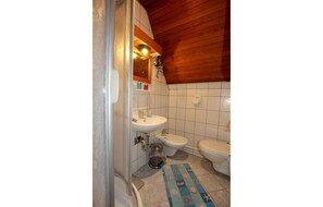 Et badeværelse med træloft, håndvask, toiletbidét og toilet.