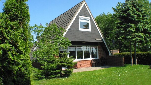 Ein modernes Haus mit Satteldach, großen Fenstern und einer Ziegel-Fassade.