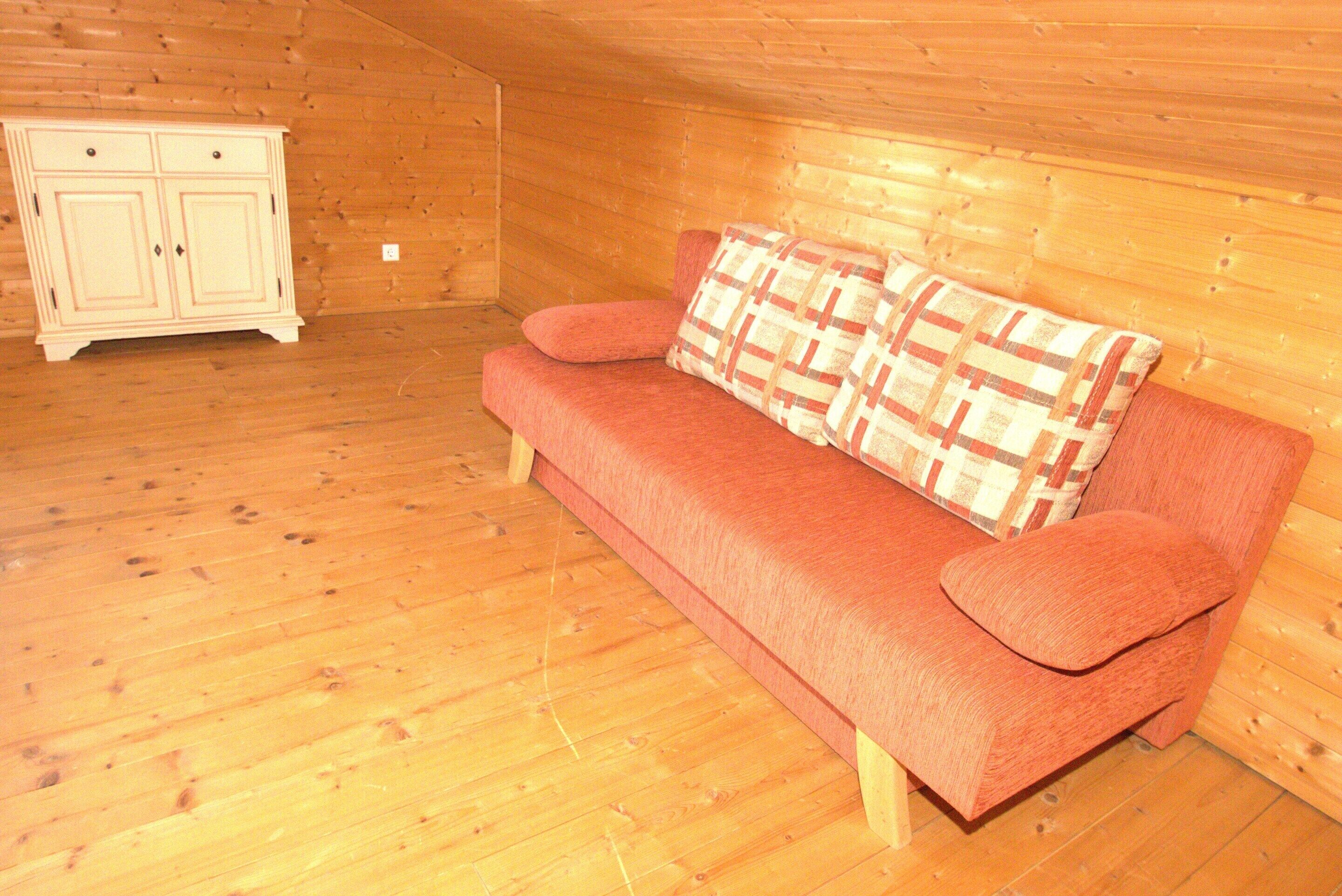 Ein Holzinnenraum mit einem roten Sofa und einem weißen Schrank.