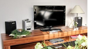 Un mobile in legno contenitore multimediale con televisore a schermo piatto, un altoparlante e un telecomando.