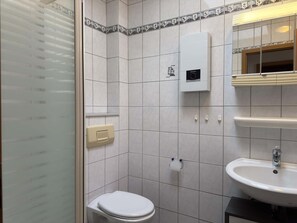 Une salle de bain équipée de toilettes, d’un lavabo, d’un miroir et d’un distributeur de serviettes.