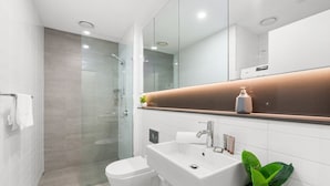 A modern bathroom with a glass-enclosed shower, a white sink, and a large mirror. - 1-bed Unit With Alfresco Dining and BBQ (Sydney)