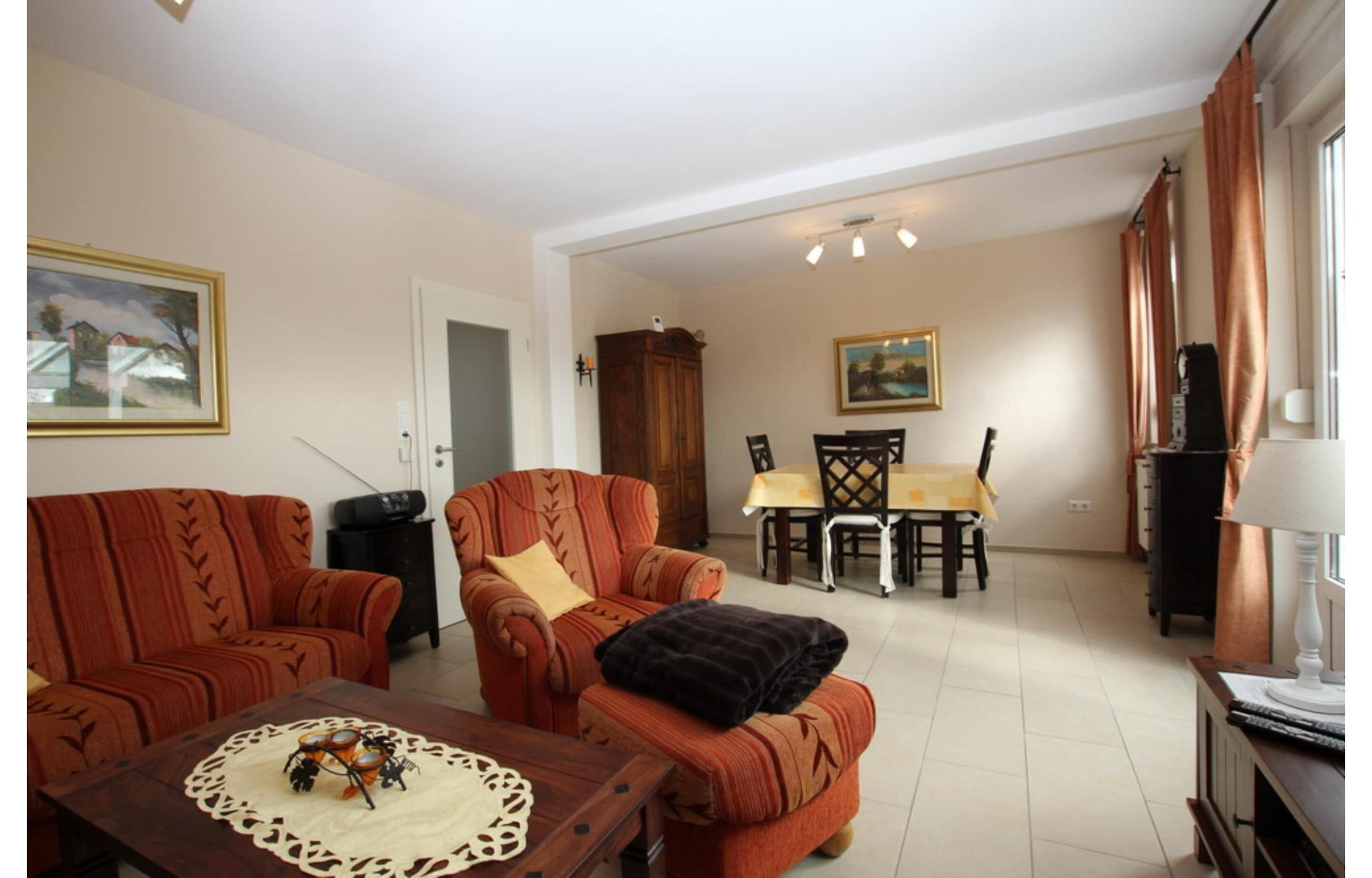 A living room with a sofa, armchair, dining table, and chairs.