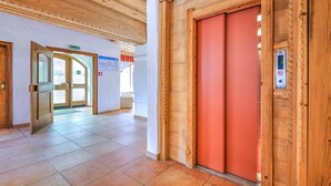 Un hall d’hôtel avec un plafond en bois, un ascenseur rouge et un sol carrelé.
