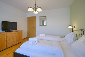 A hotel room with two beds, a wooden wardrobe, a television, a mirror, and a chandelier. - Vicky Apartment With Infrared Cabin (Wildschönau)