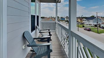 A wooden porch with two rocking chairs and a view of a residential street.