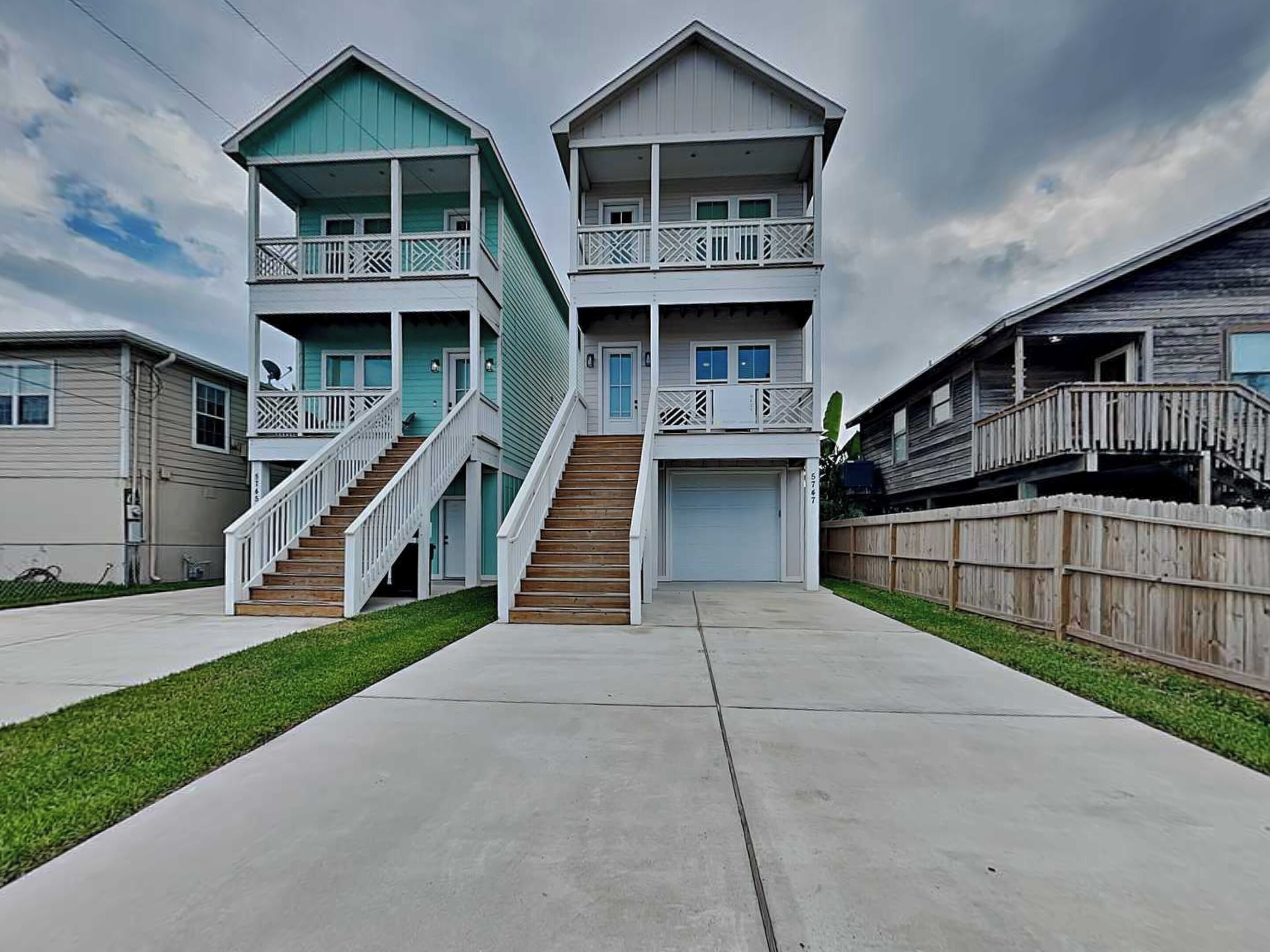A two-story residential building with a central staircase, a garage, and a wooden fence.