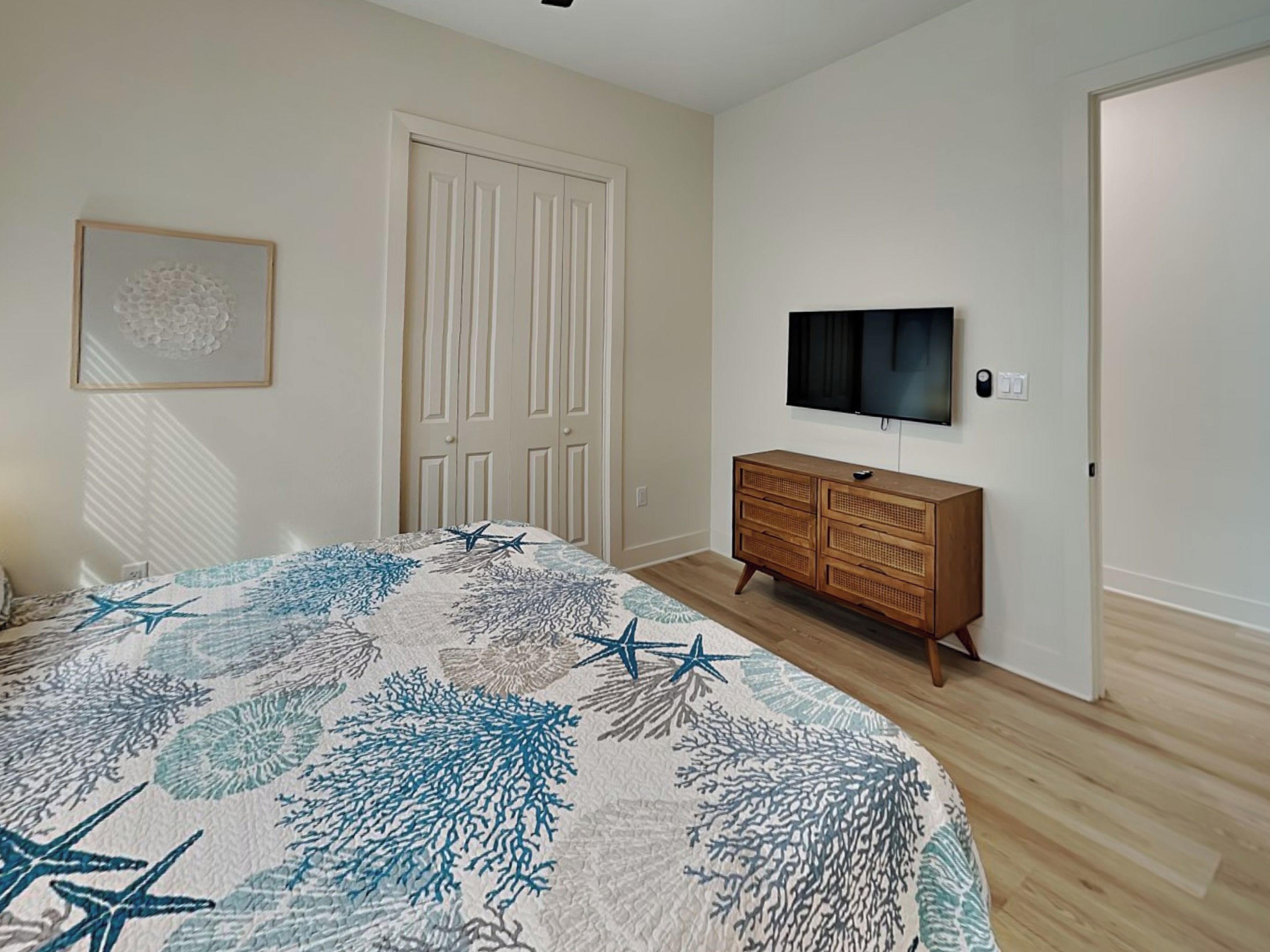 A bedroom with a bed, a dresser, a television, and a door.