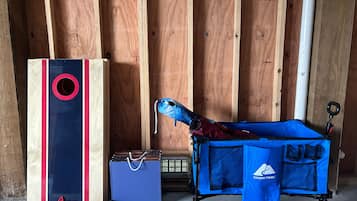 A room with wooden walls, a blue storage cart, a blue bag, and a red and black box.