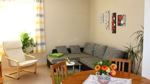 En stue med sofa, to stole, sofabord med blomster og et spisebord.