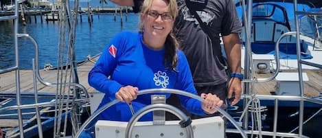 Eine Person steuert ein Boot, während sich eine andere Person dahinter aufhält.
