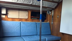 Una panca blu con un palo metallico al centro, pannelli in legno e una parete bianca.