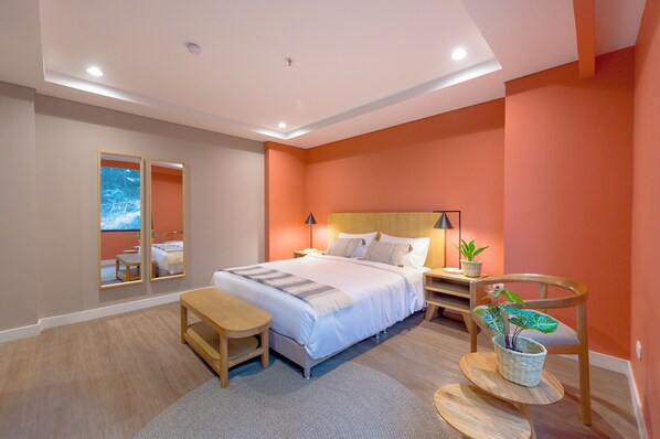 Un dormitorio moderno con una cama grande, mesitas de noche, un escritorio y una silla.