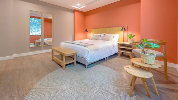 A modern bedroom with a bed, bedside tables, a nightstand, a mirror, and a potted plant. - Calucé Tesoro by letoH (Medellín)