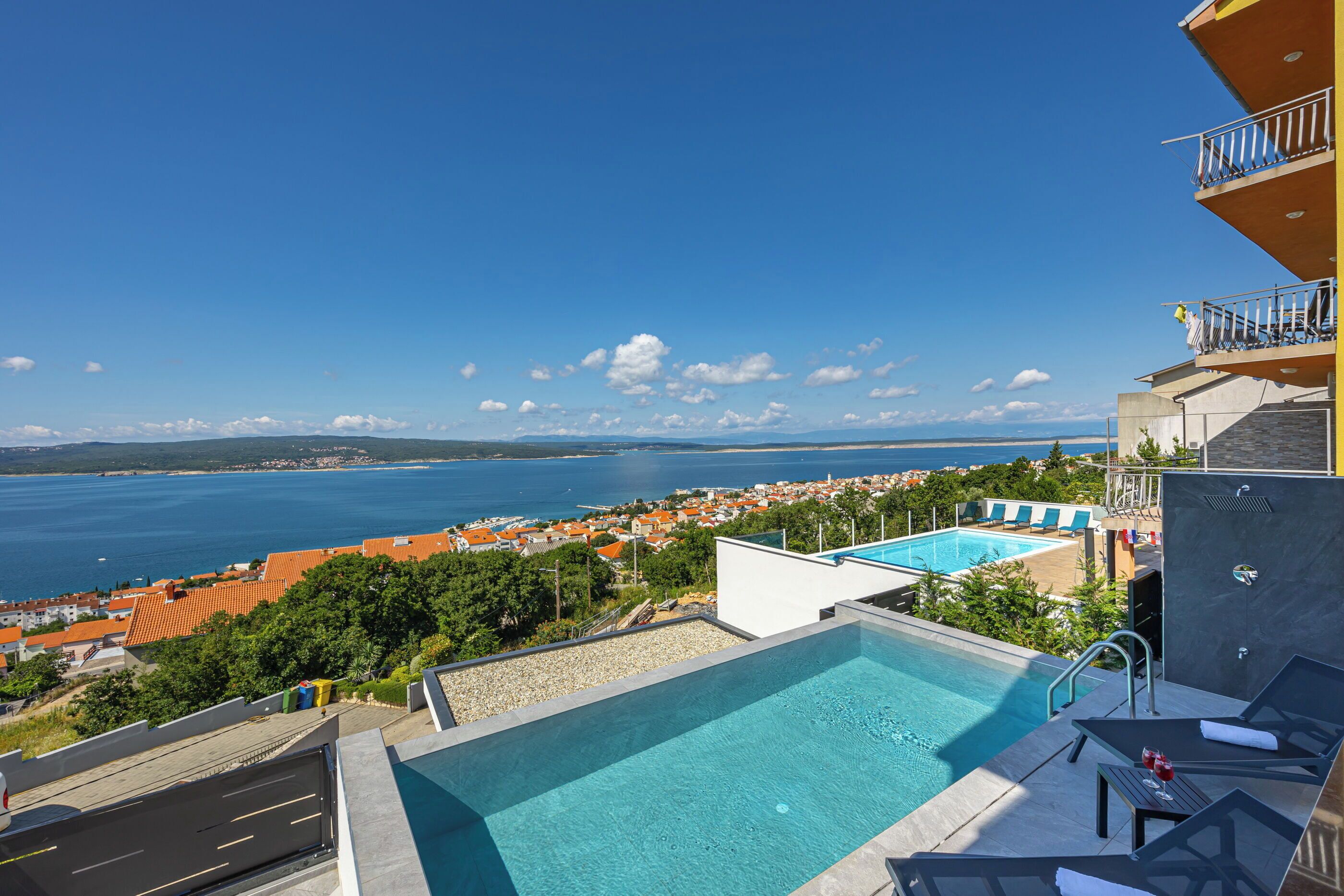 A rooftop pool with a view of the sea and a town.