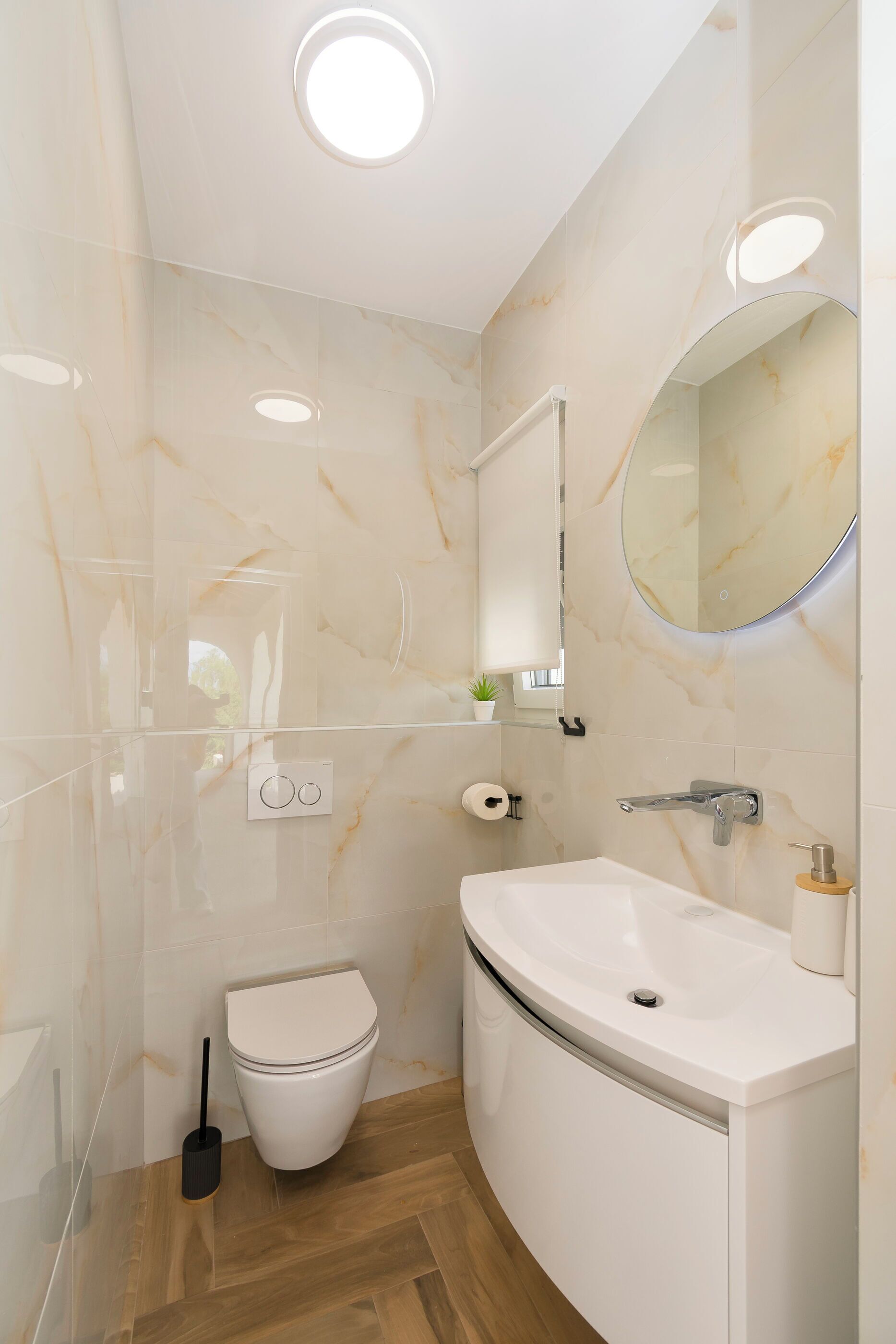 A modern bathroom with a toilet, sink, mirror, and glass shower enclosure.