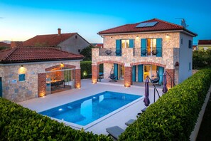 A two-story house with a swimming pool, stone exterior, and a balcony with outdoor furniture. - Villa Batana (Sukosan)