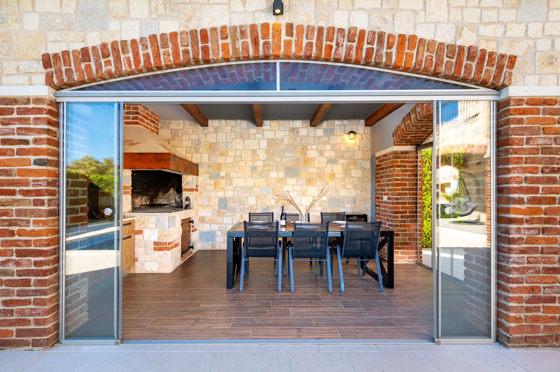 Un pati exterior amb una paret de pedra, un arc de rajola i una barbacoa de obra.