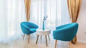 A modern room with two teal armchairs, a white round table, and a vase with blue flowers. - Villa Roko (Malinska-Dubasnica)