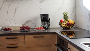 A kitchen with marble countertops, a coffee maker, a bowl of fruit, and a 'TEA' sign. - Villa Residence Sunrise (Privlaka)