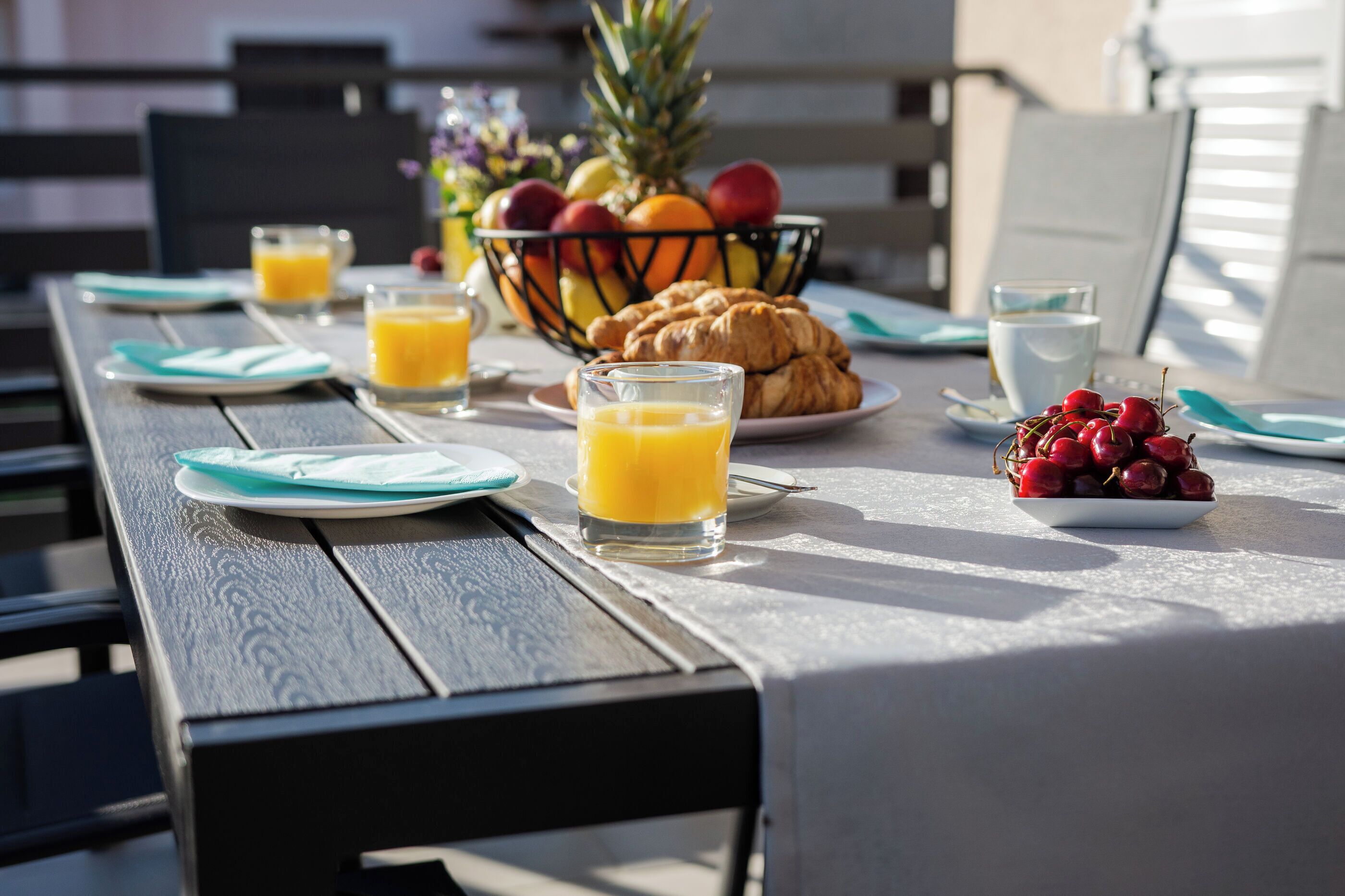 Una tavola imbandita con cornetti, frutta e succo d'arancia.