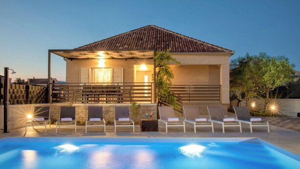 A modern house with a swimming pool, outdoor seating, and a well-lit entrance. - Villa Residence Sunrise (Privlaka)