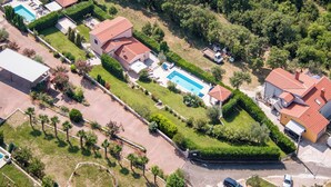 Vista aerea di una zona residenziale con case, una piscina e un giardino curato.