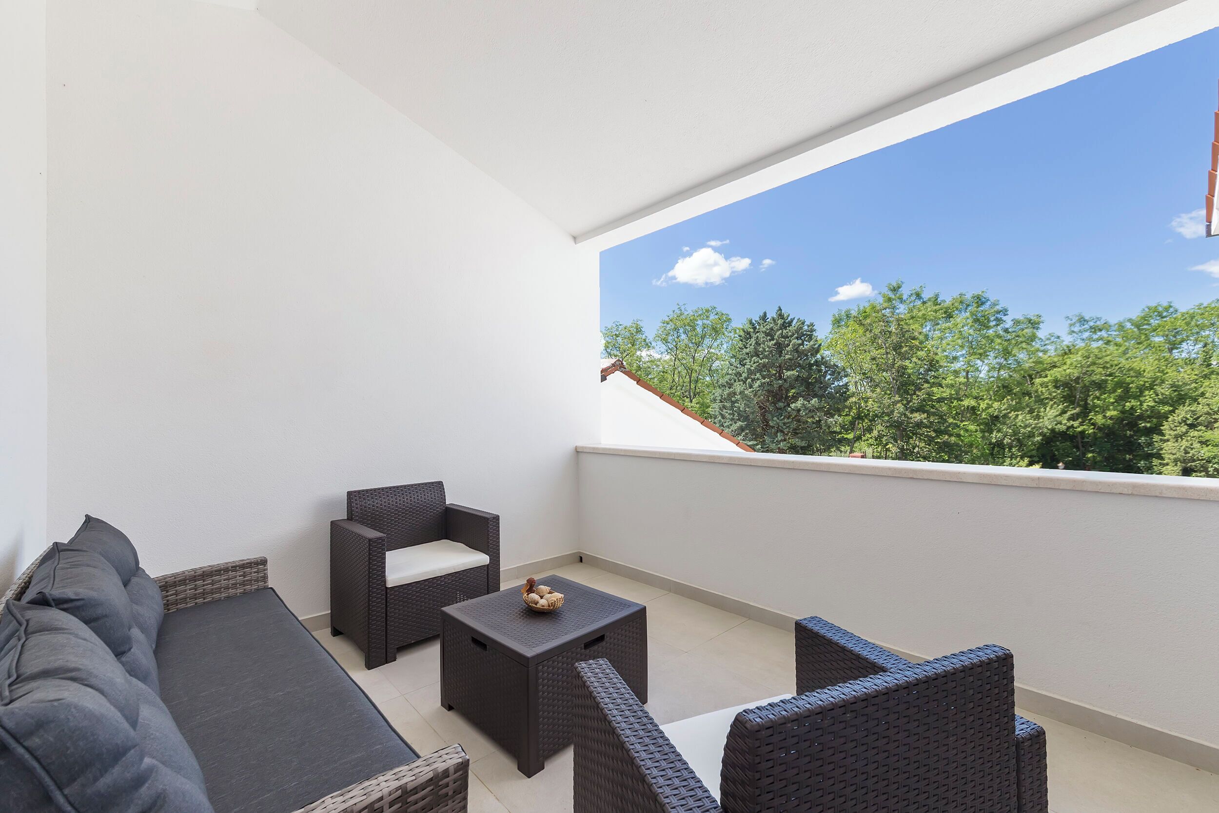 Un balcone con mobili in vimini, un divano e un tavolino.