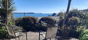 Un patio con dos sillas de metal y vista al mar.
