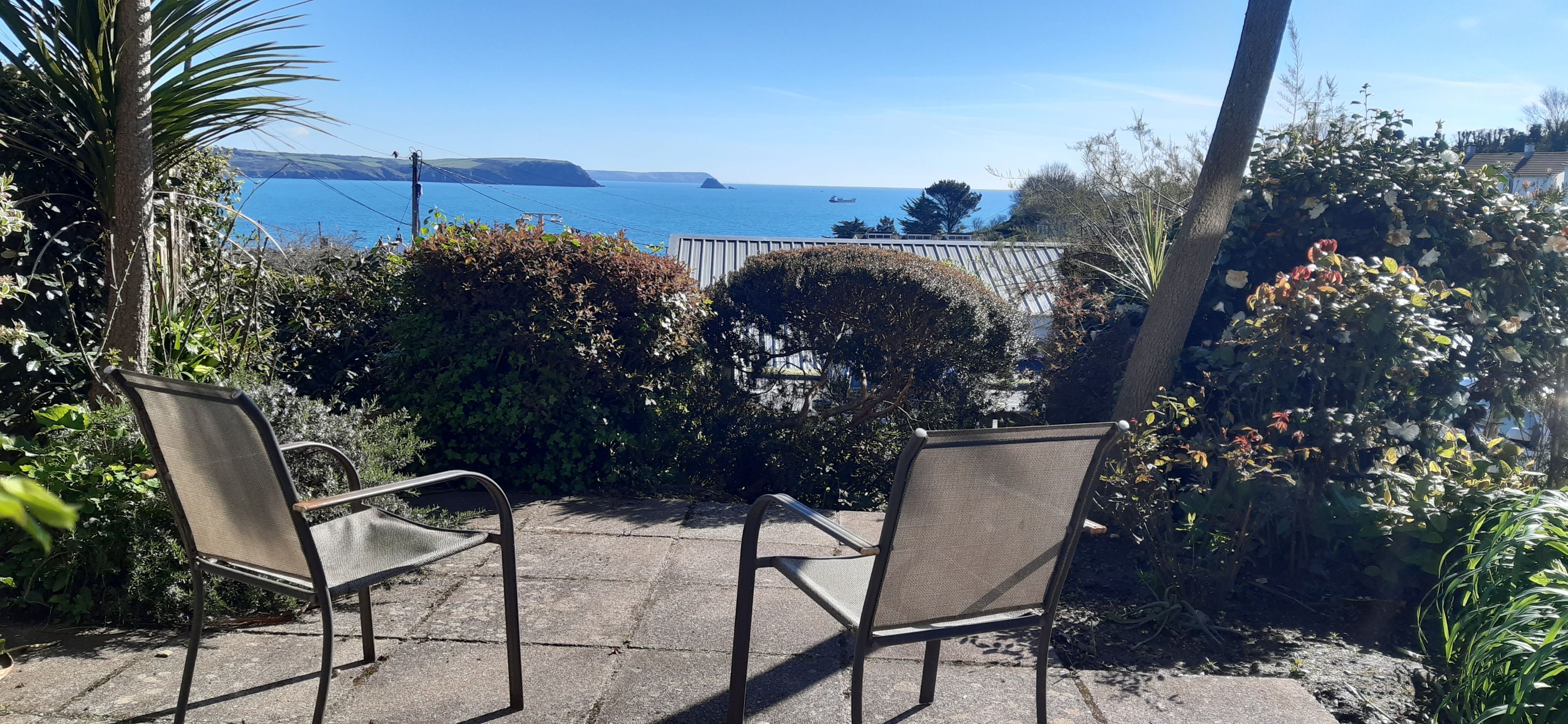 Two chairs facing a garden with a view of the sea.
