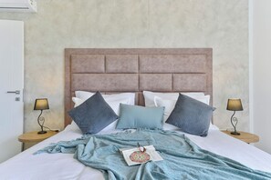 A neatly made bed with a patterned throw, two bedside lamps, and a wall-mounted air conditioner. - Villa Jomani (Bibinje)