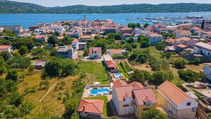 A coastal village with traditional red-tiled roofs, a marina, and a clear view of the sea. - Villa Holiday Reunion (Pirovac)