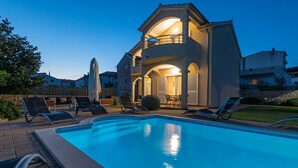 A swimming pool with lounge chairs and a building with a balcony. - Villa Holiday Reunion (Pirovac)