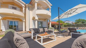 A modern outdoor living area with a sofa set, a coffee table, and a poolside lounge. - Villa Holiday Reunion (Pirovac)