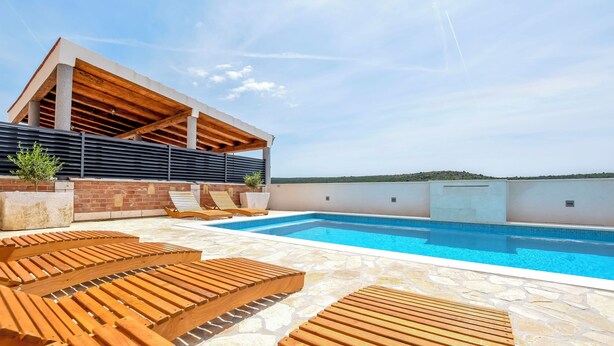 A modern outdoor pool area with wooden loungers and a covered seating area. - Villa Grgo (Rogoznica)