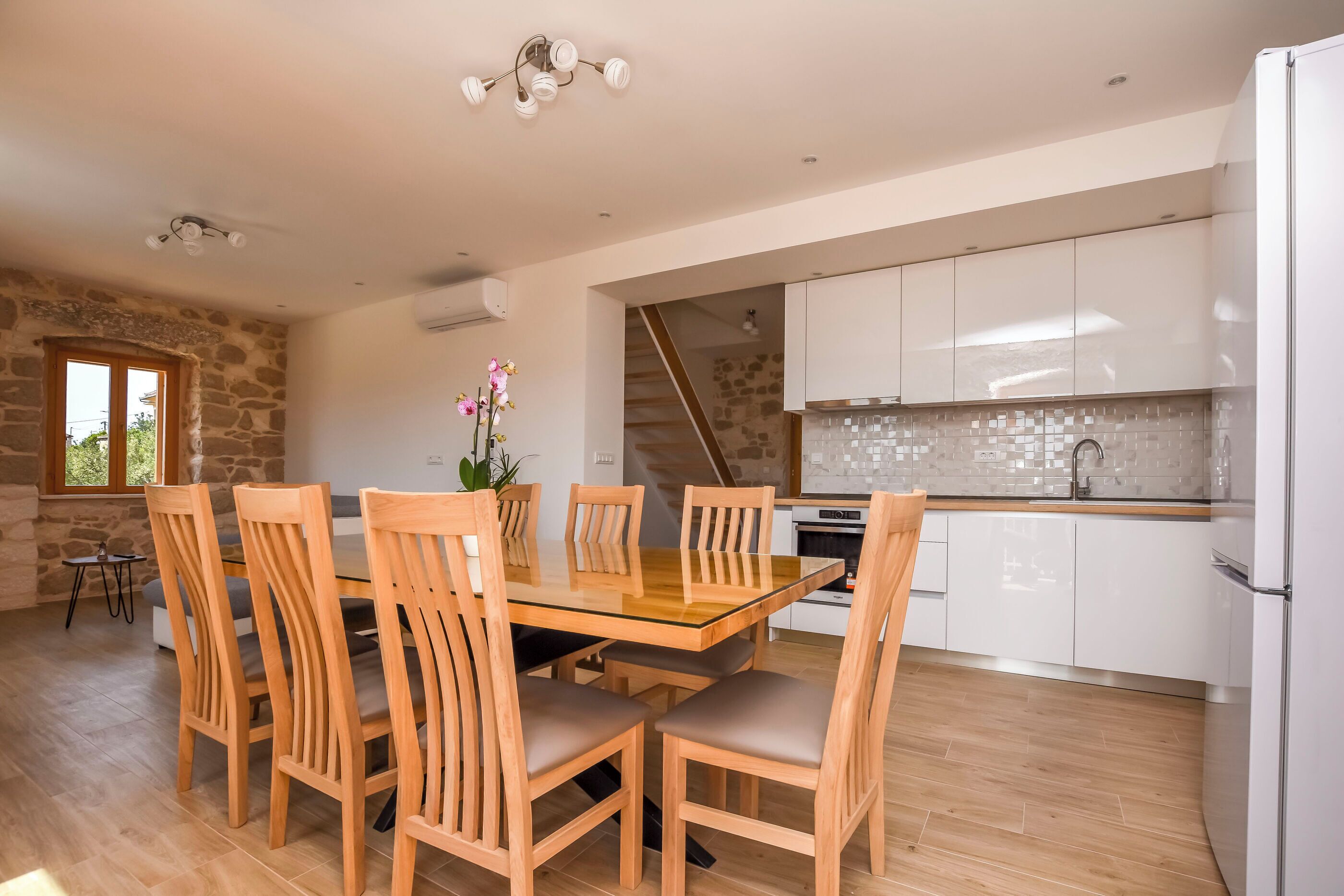 A modern kitchen with white cabinets, a tiled backsplash, and a built-in oven.