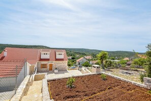 A residential area with houses, a garden, and a hilly landscape in the background. - Villa Grgo (Rogoznica)