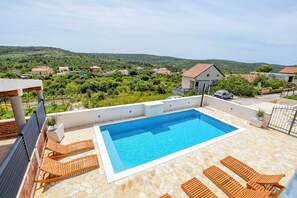 A rooftop swimming pool with wooden loungers and a stone-tiled deck. - Villa Grgo (Rogoznica)