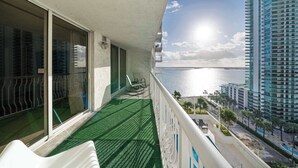 Un balcón con vista al mar y un edificio alto.