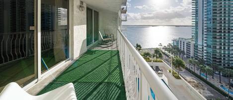 Un balcon avec vue sur la mer et un immeuble imposant.