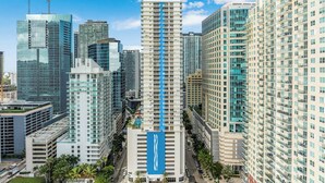 Un edificio alto con una llamativa banda vertical azul, rodeado de otros edificios en un paisaje urbano.