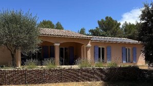 Una casa con techo de tejas, pared de piedra y un campo seco cubierto de hierba.