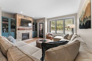 Een moderne woonkamer met een stenen openhaard, een groot raam met uitzicht op de omgeving en een gezellige zithoek.