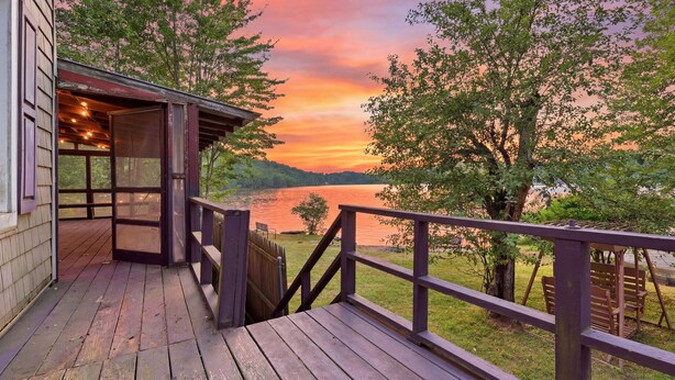 Una terraza de madera con vista a un lago y al atardecer.